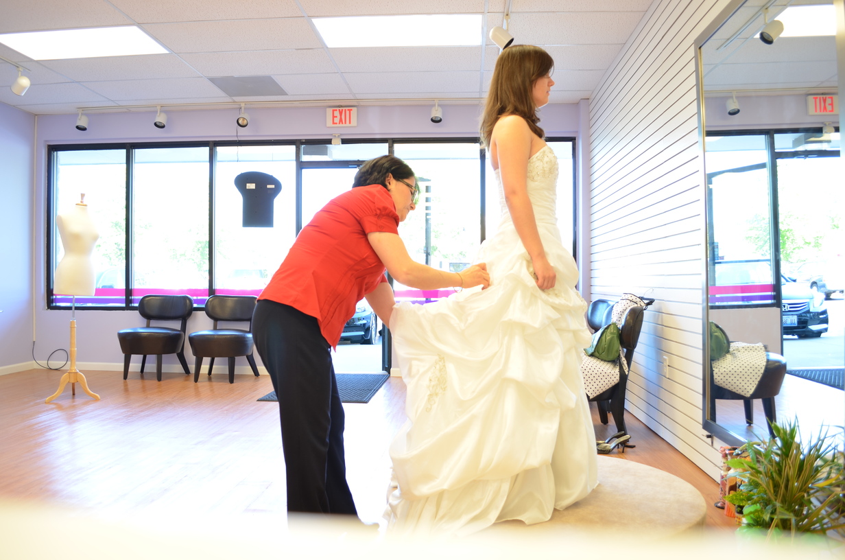 Mahnaz inspecting the back of a bridal dress.